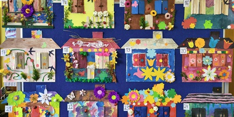 Powiększ grafikę: Tablica, na której wiszą kolorowe prace plastyczne przedstawiające domy pani wiosny.