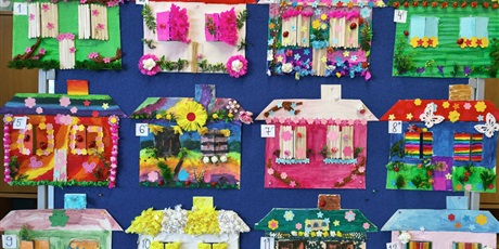 Powiększ grafikę: Tablica, na której wiszą kolorowe prace plastyczne przedstawiające domy pani wiosny.