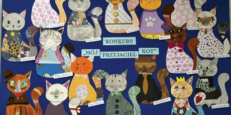 Powiększ grafikę: Granatowa tablica ścienna z pracami plastycznymi przedstawiającymi kolorowe koty.