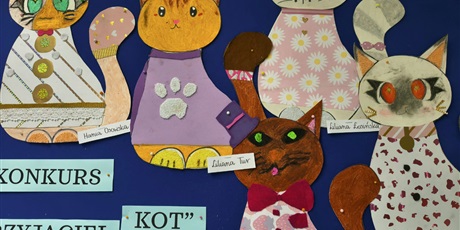 Powiększ grafikę: Granatowa tablica ścienna z pracami plastycznymi przedstawiającymi kolorowe koty.