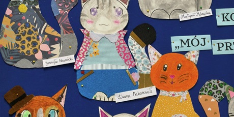 Powiększ grafikę: Granatowa tablica ścienna z pracami plastycznymi przedstawiającymi kolorowe koty.