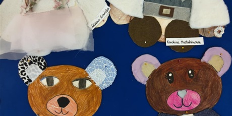 Powiększ grafikę: Granatowa tablica ścienna, na której wiszą kolorowe misie wyklejone tkaninami, piankami itp.