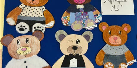 Powiększ grafikę: Granatowa tablica ścienna, na której wiszą kolorowe misie wyklejone tkaninami, piankami itp.