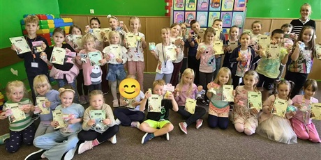Powiększ grafikę: Grupa dzieci wraz z nauczycielką pozuje do zdjęcia. W rękach trzymają dyplomy i nagrody