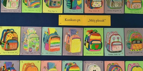 Powiększ grafikę: Granatowa tablica, na której wiszą prace konkursowe przedstawiające kolorowe plecaki.
