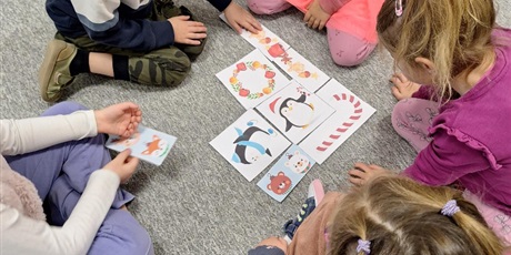 Powiększ grafikę: Dzieci siedzą w kole na dywanie i układają obrazki.