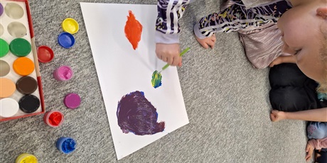 Powiększ grafikę: Dziecko maluje farbami plakatowymi.