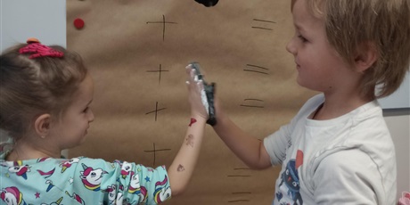 Powiększ grafikę: Uczniowie oddziału przedszkolnego przyciskają do siebie dłonie zanurzone w farbie.