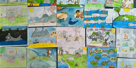 Powiększ grafikę: Kilkanaście kolorowych prac konkursowych leży obok siebie na dywanie. Znajdują się na nich koty, słonie, kury, wieloryby itp.