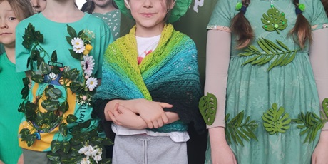 Powiększ grafikę: Dzieci ubrane na zielono stoją w grupie na holu szkolnym.