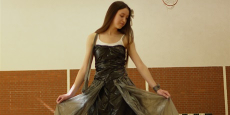 Powiększ grafikę: Na zdjęciu uczennica pozuje w stroju ekologicznym. Sukienka w kolorze czarnym i zielonym zrobiona jest z worków foliowych.