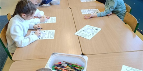 Powiększ grafikę: Grupa dzieci przy stole koloruje karty pracy "Moje pasje". 