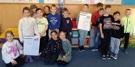 Powiększ grafikę: Zdjęcie grupowe dzieci ze świetlicy. Dwójka dzieci trzymają plakat "Słowniczek Zazdrości"