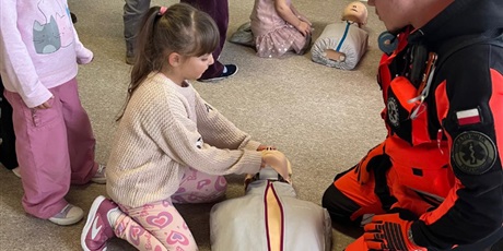 Powiększ grafikę: Dzieci klęczą przy manekinach i samodzielnie próbują udzielać pierwszej pomocy.