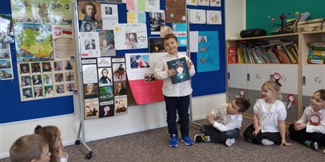 Powiększ grafikę: Chłopiec prezentuje efekt swojej pracy. W ręku trzyma książke. Opowiada o znanej postaci.