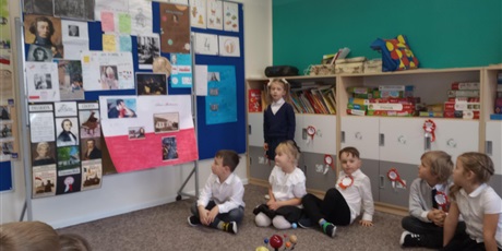 Powiększ grafikę: Dziewczynka stoi przy tablicy i opowiada dzieciom kolejnym sławnym Polaku.