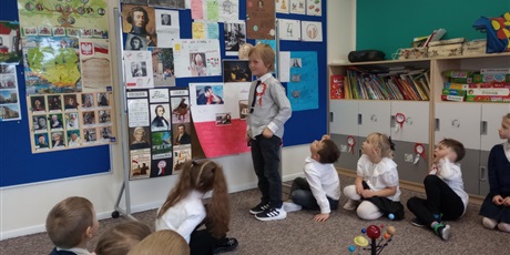 Powiększ grafikę: Chłopiec z uśmiechem opowiada o znanym Polaku. Dzieci są zasłuchane.