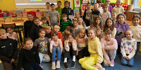 Powiększ grafikę: Duża grupa dzieci siedzi na dywanie przodem do obiektywu.