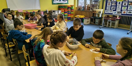 Powiększ grafikę: Grupa dzieci siedzi przy stole w świetlicy. W skupieniu kolorują obrazki.