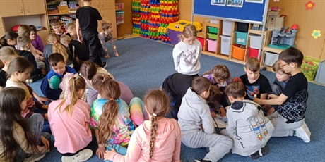 Powiększ grafikę:  Grupy dzieci siedzą na dywanie w świetlicy.  Pochylają się  nad wyklejankami kaszubskimi.
