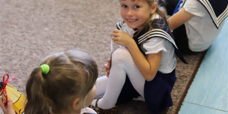 Powiększ grafikę: Ubrane na galowo dziewczynki oczekują na pasowanie. Są radosne ale i podekscytowane.