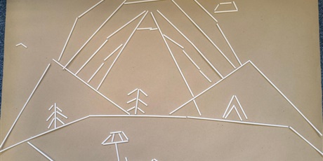 Powiększ grafikę: Na zdjęciu znajduje się plansza przedstawiająca kompozycję wykonaną z plastikowych patyków. Widać góry, tęczę, drzewa.
