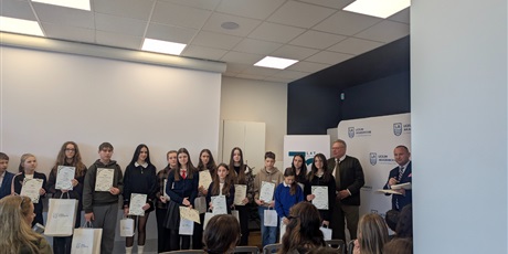 Powiększ grafikę: Grupa nagrodzonych uczniów z dyplomami i nagrodami w rękach oraz organizatorzy konkursu.