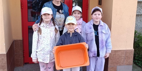 Powiększ grafikę: Cztery dziewczynki i ich nauczycielka pozują do zdjęcia. Dziewczynka w środku trzyma puste pudełko