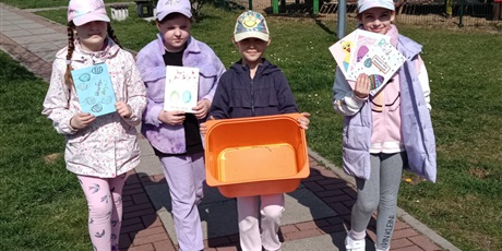 Powiększ grafikę: Cztery dziewczynki idą. Trzy z nich trzymają kartki wielkanocne, a jedna trzyma puste pomarańczowe pudełko