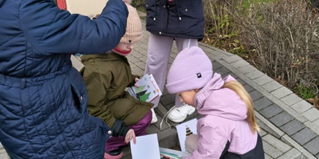 Powiększ grafikę: Dziewczynki pochylają się nad pudełkiem. Wyciągają z niego kartki bożonarodzeniowe.