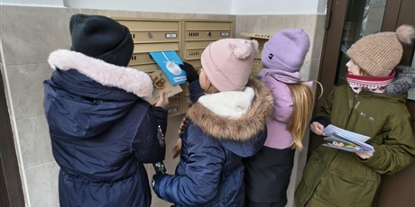 Powiększ grafikę: Dziewczynki wrzucają do skrzynek pocztowych kartki z życzeniami bożonarodzeniowymi.