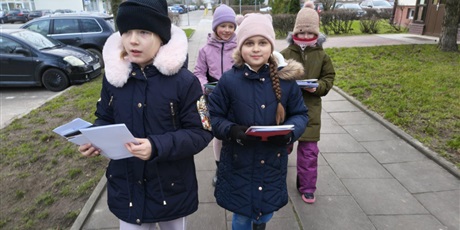 Powiększ grafikę: Cztery dziewczynki idą niosą  uniesione do góry kartki bożonarodzeniowe.