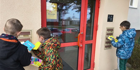 Powiększ grafikę: Trzech chłopców wrzuca kartki świąteczne do skrzynek pocztowych. Chłopcy są widoczni tyłem.