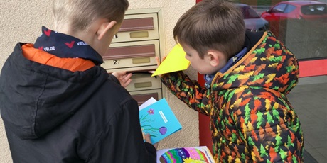 Powiększ grafikę: Dwóch chłopców wrzuca kartki świąteczne do skrzynek pocztowych. Chłopcy są widoczni tyłem.