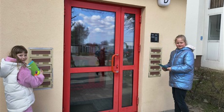 Powiększ grafikę: Dwie dziewczynki wrzucają kartki świąteczne do skrzynek pocztowych. Dziewczynki patrzą w obiektyw. 