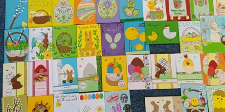 Powiększ grafikę: Kilkadziesiąt prostokątnych kartek wielkanocnych ułożone w szachownicę.