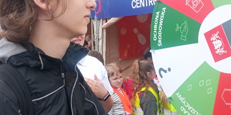 Powiększ grafikę: Chłopiec w czarnej kurtce kręci kołem w loterii ekologicznej. W tle widać herb Gdańska oraz inne dzieci.