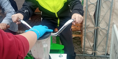 Powiększ grafikę: Chłopiec jedzie na stacjonarnym rowerze, a energia jest wykorzystana w blenderze podłączonym do roweru.