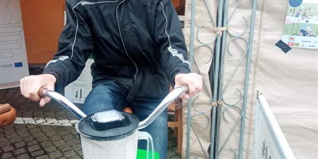 Powiększ grafikę: Chłopiec w czarnej kurtce jedzie na stacjonarnym rowerze, a energia jest wykorzystana w blenderze podłączonym do roweru.