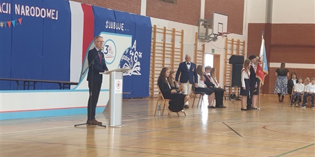 Powiększ grafikę: Dyrektor szkoły przemawia do uczniów, w głębi widać sztandar szkoły.