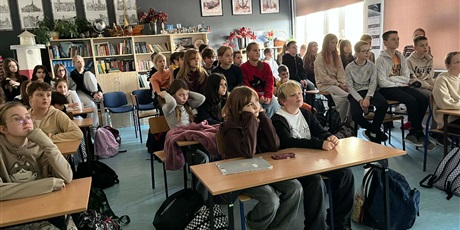 Powiększ grafikę: Zdjęcie przedstawia uczniów słuchających opowieści pracownika firmy LOTTE Wedel. Dzieci słuchają z zaciekawieniem prezentacji Jakuba.