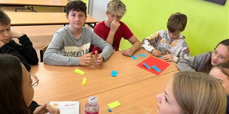 Powiększ grafikę: Dzieci siedzą przy stolikach i pracują w grupie.