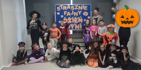 Powiększ grafikę: Grupa poprzebieranych dzieci pozuje na tle napisu: "Strasznie fajny dzień dyni". Dzieci przebrane są z apostacie z bajek, czarownice, księżniczki, dynie i piratów.