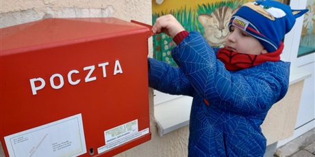 Powiększ grafikę: Chłopiec wrzuca kartkę do skrzynki pocztowej.