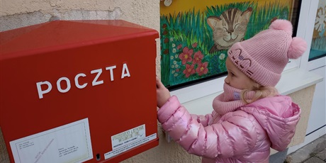 Powiększ grafikę: Dziewczynka wrzuca kartkę do skrzynki pocztowej.