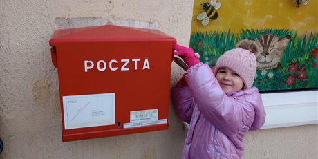 Powiększ grafikę: Dziewczynka wrzuca kartkę do skrzynki pocztowej.