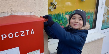 Powiększ grafikę: Chłopiec wrzuca kartkę do skrzynki pocztowej.