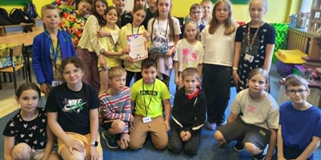 Powiększ grafikę: Grupa dzieci pozuje do zdjęcia. W rękach trzymają dyplom i worek ze słodyczami.