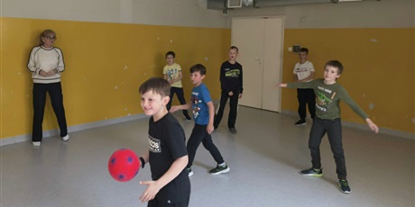 Powiększ grafikę: Grupa dzieci na sali gimnastycznej gra w dwa ognie.