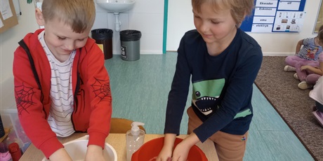 Powiększ grafikę: Dwóch chłopców pierze w miskach ubrania.